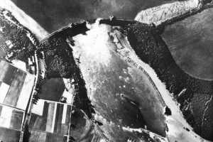 Aerial reconnaissance photograph taken on 17 May 1943 showing the breach in the Mohne Dam caused by 617 Squadron\'s raid during the previous night. The Eder Dam was breached by means of \'bouncing bombs\' designed by Barnes Wallis. This spectacular feat of precision bombing had tremendous propaganda value, although its practical effects were less great than many had hoped © Crown Copyright